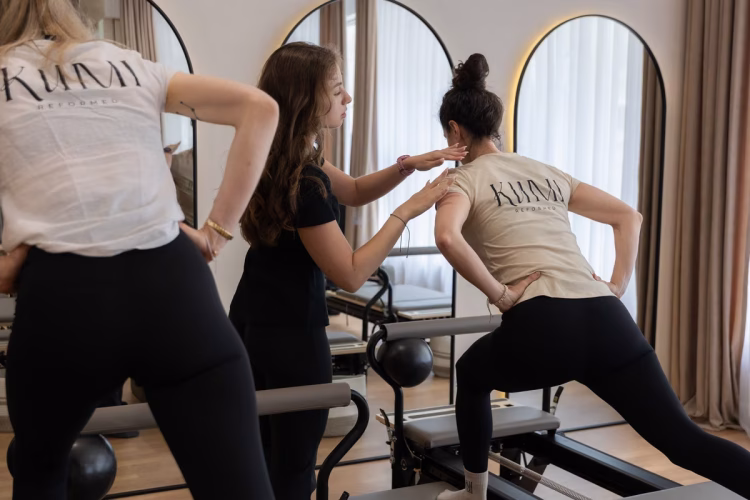 Trainerin korrigiert die Haltung beim Pilates-Training