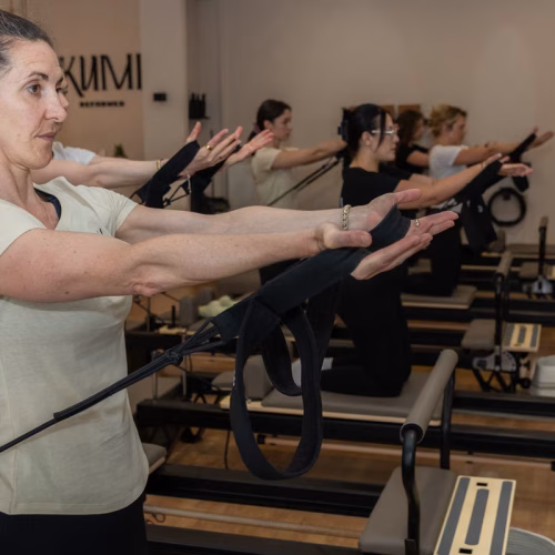 Trainerin mit Pilates-Ring am Reformer